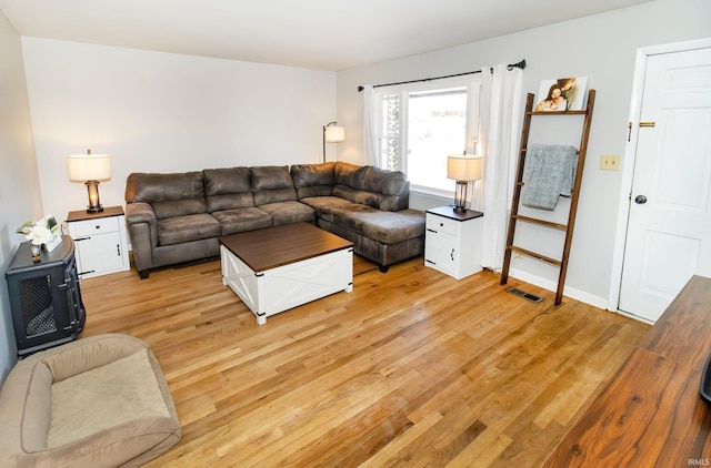 living room with visible vents, baseboards, and light wood-type flooring