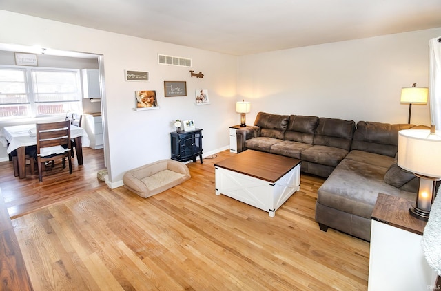 living area featuring light wood finished floors, visible vents, and baseboards