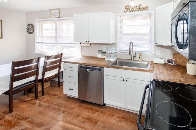 kitchen with a sink, black appliances, white cabinets, light wood-style floors, and butcher block counters