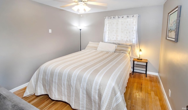 bedroom featuring ceiling fan, baseboards, and wood finished floors