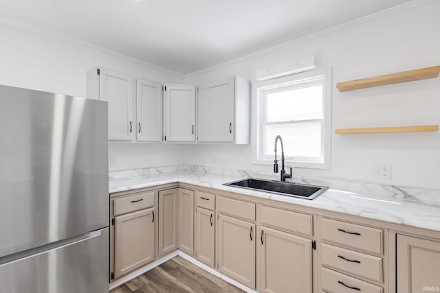 kitchen featuring wood finished floors, open shelves, freestanding refrigerator, ornamental molding, and a sink