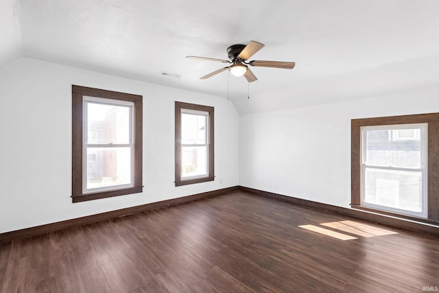 unfurnished room with visible vents, baseboards, dark wood-type flooring, and vaulted ceiling