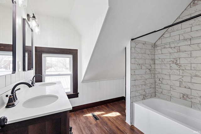 full bathroom featuring a wainscoted wall, wood finished floors, lofted ceiling, and a sink