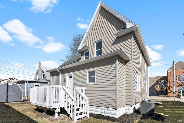 back of property with a lawn, a wooden deck, and central AC