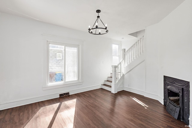 unfurnished living room with stairway, plenty of natural light, wood finished floors, and visible vents