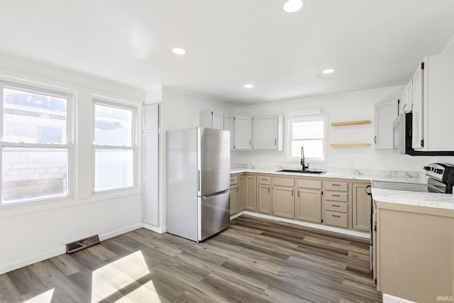 kitchen with a sink, open shelves, wood finished floors, stainless steel appliances, and light countertops