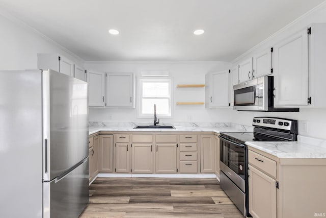 kitchen with appliances with stainless steel finishes, light wood-type flooring, crown molding, and a sink