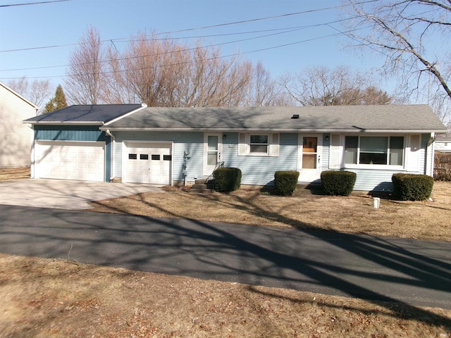 ranch-style house featuring concrete driveway, a garage, and a shingled roof