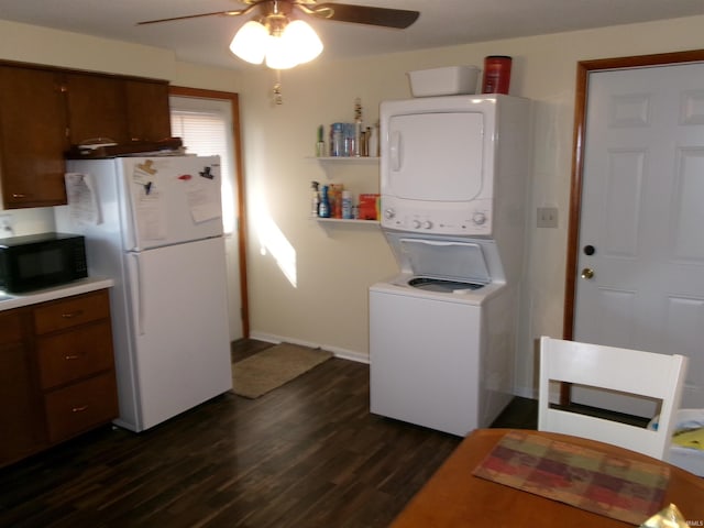 kitchen featuring freestanding refrigerator, black microwave, light countertops, stacked washer / dryer, and dark wood-style flooring