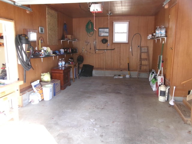 garage with a workshop area, wooden walls, and a garage door opener