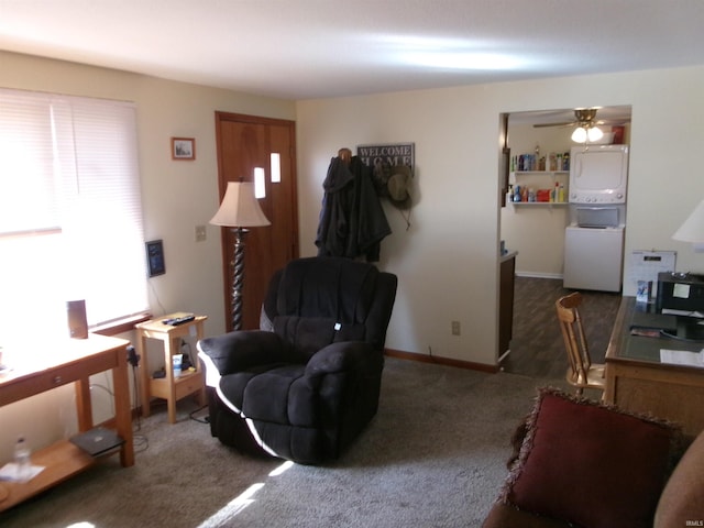 carpeted living area with stacked washer and clothes dryer and baseboards