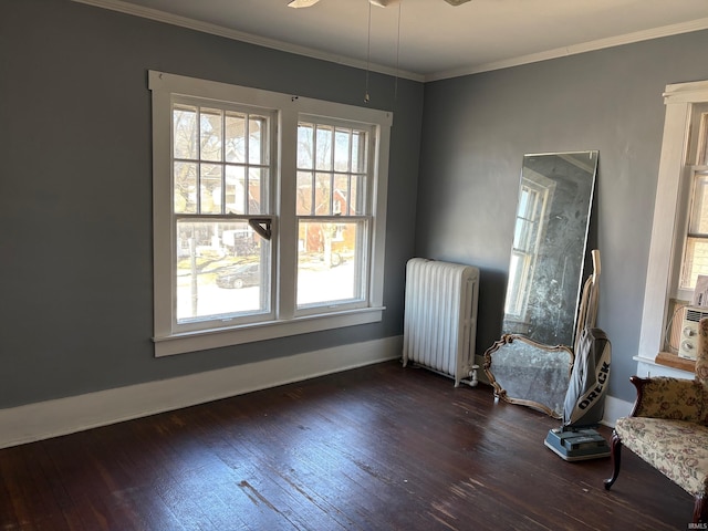 empty room featuring a ceiling fan, baseboards, radiator heating unit, dark wood-style flooring, and crown molding