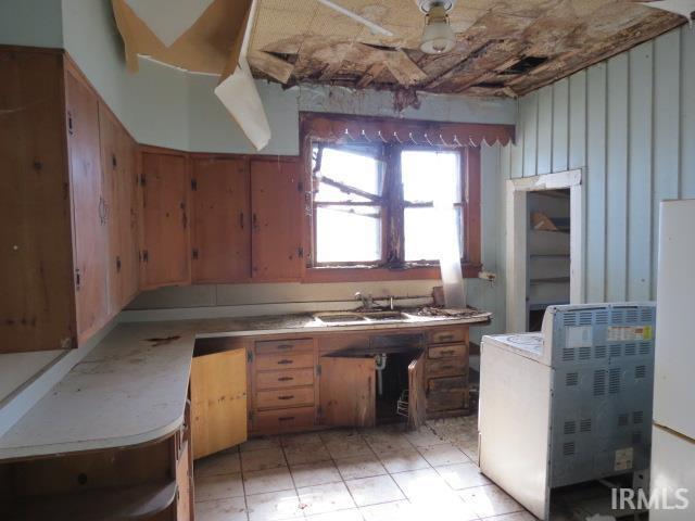 kitchen with light tile patterned floors, brown cabinets, light countertops, and a sink