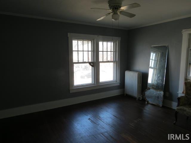 unfurnished room with radiator, dark wood-type flooring, baseboards, ceiling fan, and ornamental molding