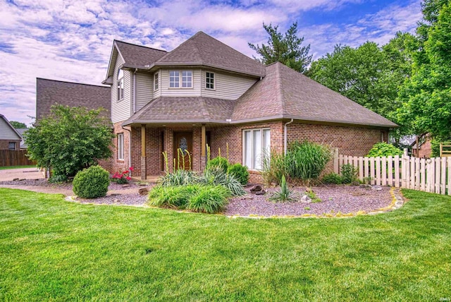 view of front facade with brick siding, a front lawn, and fence