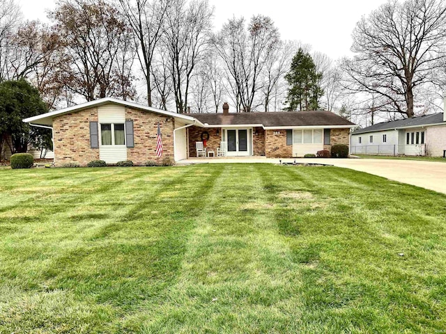 ranch-style home featuring a front lawn, brick siding, driveway, and a chimney