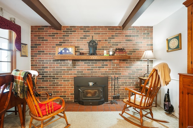 sitting room featuring beam ceiling, brick wall, and a wood stove