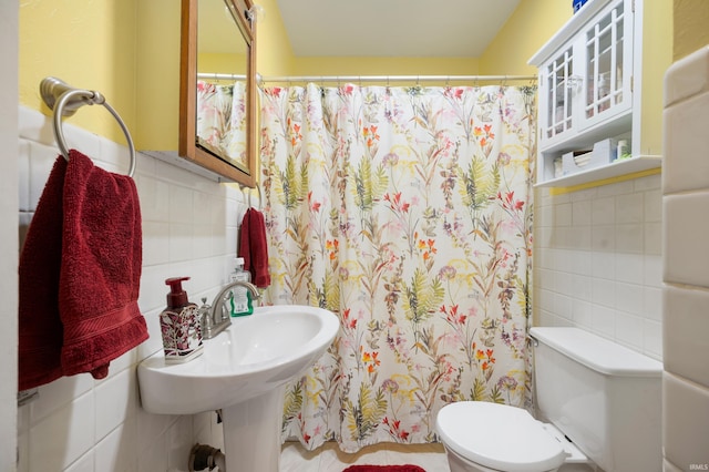 bathroom with a shower with curtain, tile walls, toilet, and a sink