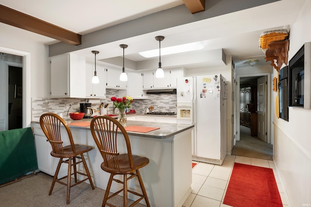 kitchen featuring under cabinet range hood, backsplash, white fridge with ice dispenser, a peninsula, and light tile patterned flooring