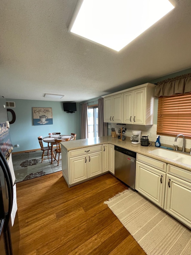 kitchen featuring dark wood-type flooring, a sink, a peninsula, light countertops, and dishwasher