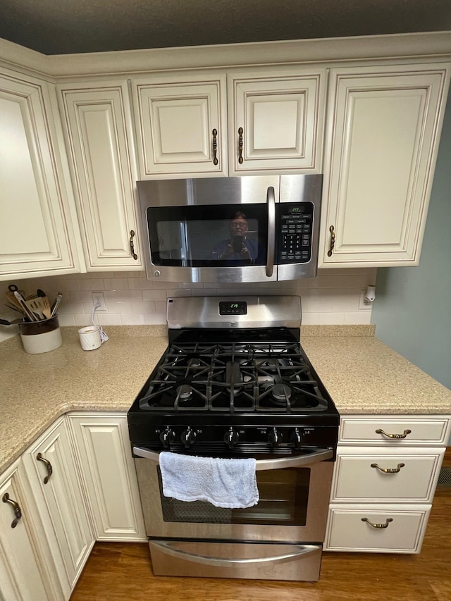 kitchen with stainless steel appliances, backsplash, and wood finished floors