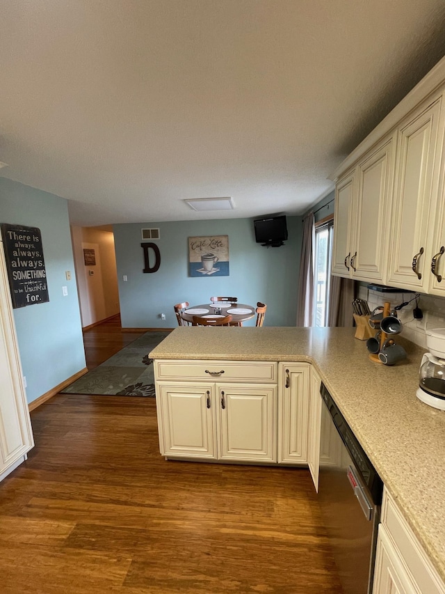 kitchen featuring visible vents, dark wood finished floors, a peninsula, light countertops, and dishwasher