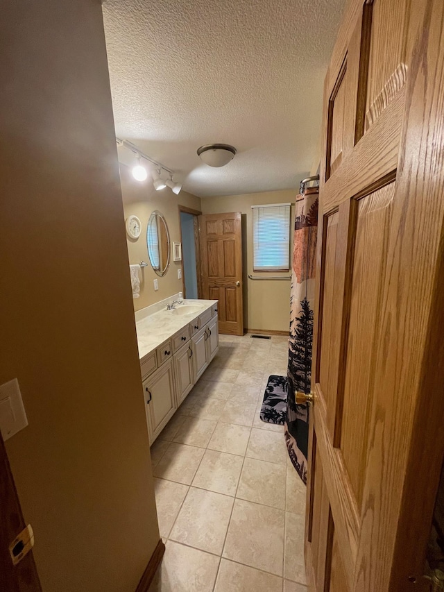 full bathroom featuring a shower with curtain, a textured ceiling, vanity, and tile patterned flooring