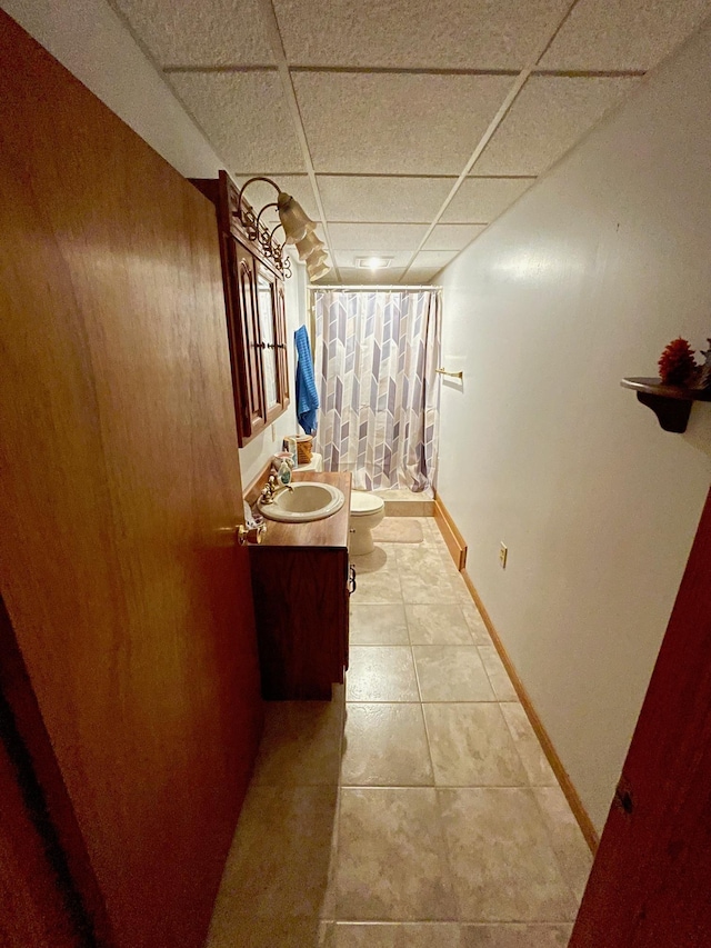 bathroom featuring vanity, a shower with shower curtain, a drop ceiling, tile patterned floors, and toilet