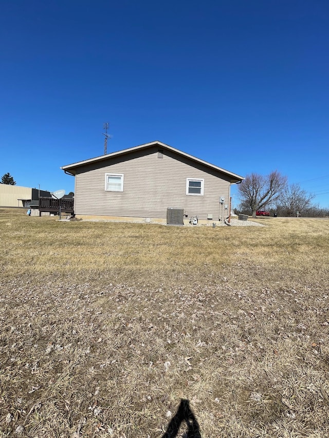 view of side of property featuring central AC unit and a lawn