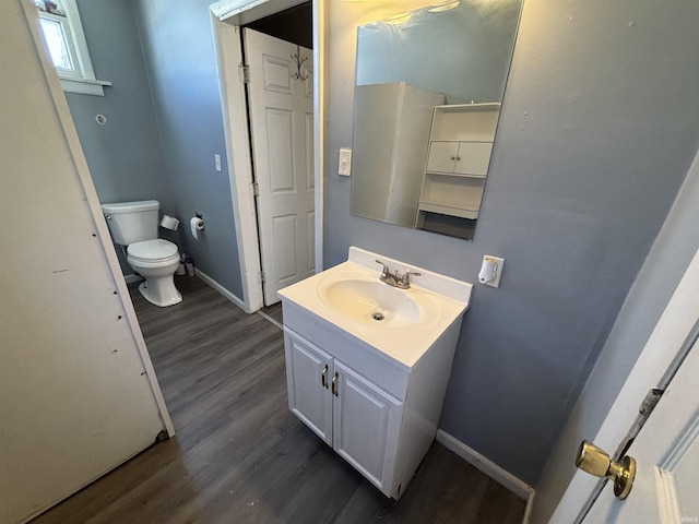 bathroom with vanity, toilet, wood finished floors, and baseboards