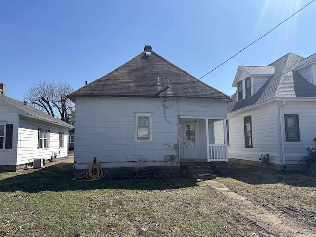 back of house with a lawn and roof with shingles