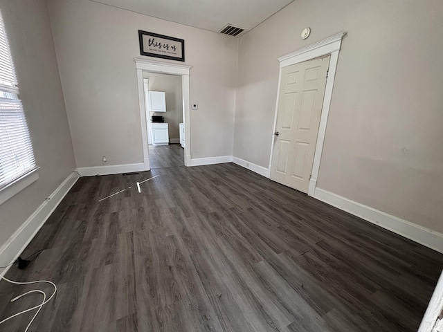 unfurnished room featuring visible vents, baseboards, and dark wood-style floors