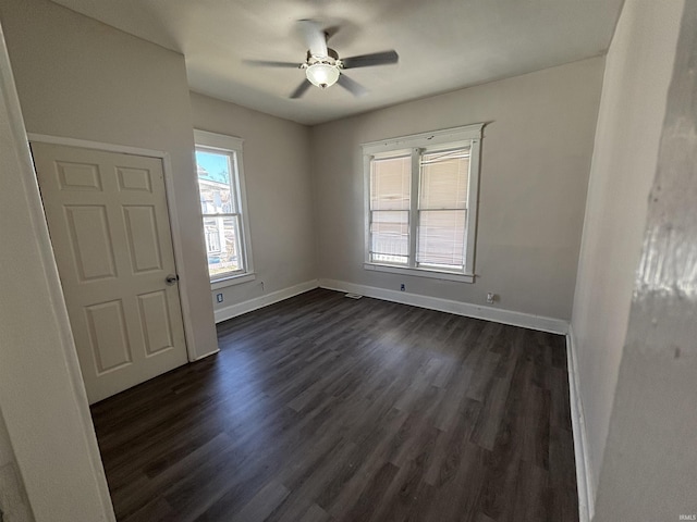 spare room featuring ceiling fan, baseboards, and dark wood-style floors