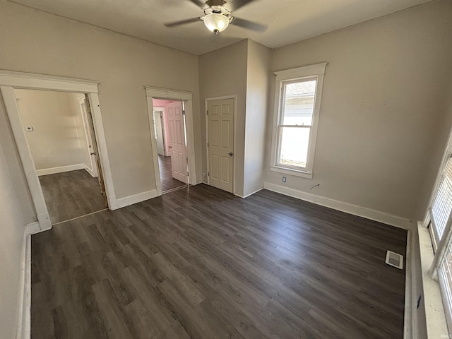 unfurnished bedroom with visible vents, baseboards, dark wood-type flooring, and a ceiling fan