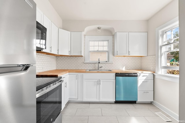 kitchen featuring visible vents, a sink, decorative backsplash, appliances with stainless steel finishes, and butcher block counters