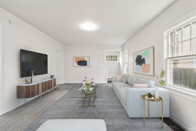 carpeted living area featuring arched walkways and baseboards