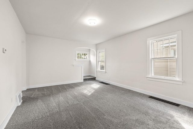 spare room with visible vents, dark carpet, and baseboards