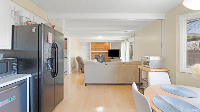 kitchen with light wood-type flooring, beam ceiling, a textured ceiling, and appliances with stainless steel finishes