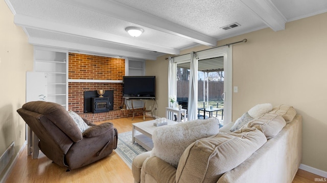 living area with visible vents, beam ceiling, a textured ceiling, and wood finished floors