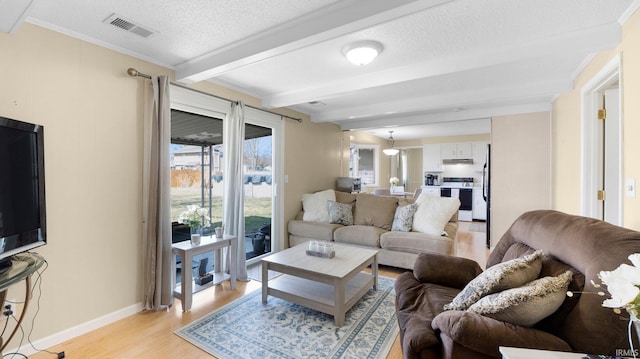 living area with visible vents, beam ceiling, a textured ceiling, crown molding, and light wood-type flooring