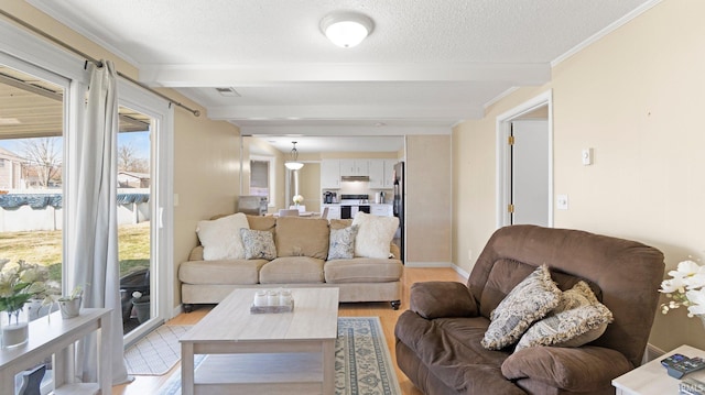 living area with baseboards, ornamental molding, beam ceiling, light wood-style floors, and a textured ceiling