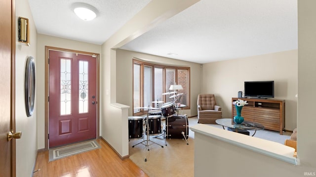 entryway featuring light wood-style floors, baseboards, and a textured ceiling