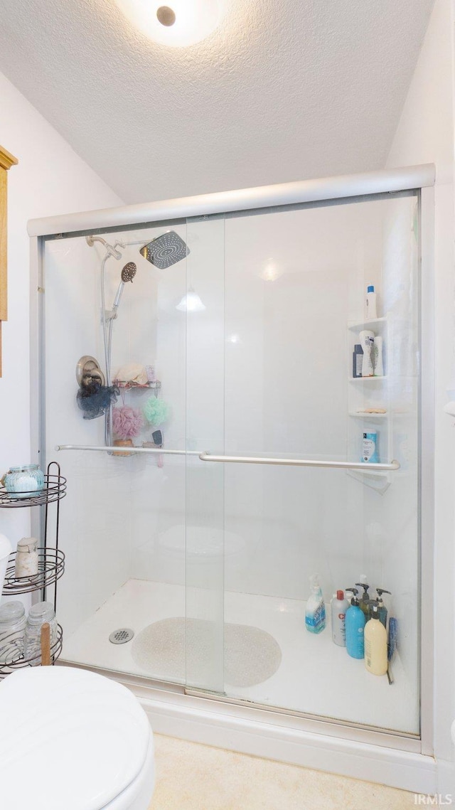 full bath featuring toilet, a stall shower, and a textured ceiling