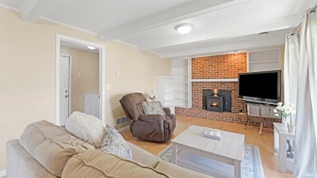 living area featuring visible vents, beamed ceiling, ornamental molding, and light wood finished floors