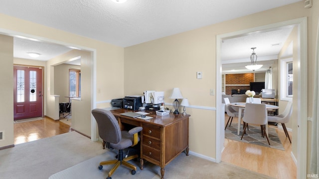 carpeted home office featuring baseboards, a textured ceiling, and wood finished floors