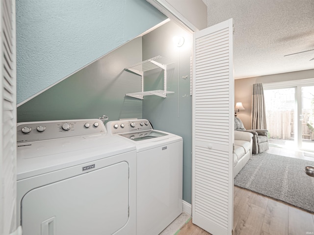 laundry area featuring a textured ceiling, laundry area, light wood finished floors, and washer and clothes dryer