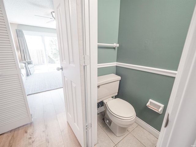 bathroom with tile patterned flooring, toilet, baseboards, and ceiling fan