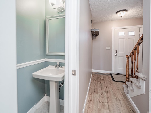 interior space with a sink, baseboards, a textured ceiling, and wood finished floors