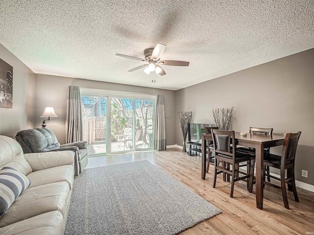 living room with a ceiling fan, light wood-style floors, baseboards, and a textured ceiling