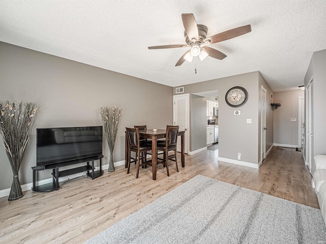 dining space featuring a textured ceiling, baseboards, and wood finished floors